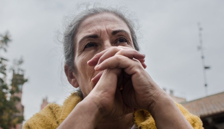 An elderly woman with her hands on her face.