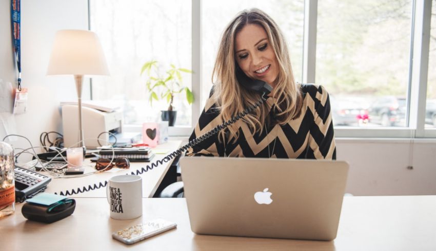 A woman is talking on the phone while sitting at a desk.