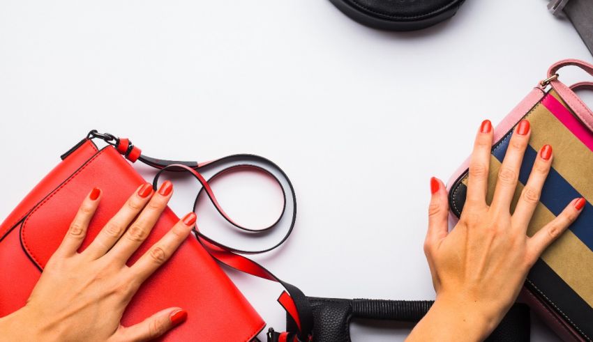 A woman's hands are holding a red purse and a black purse.
