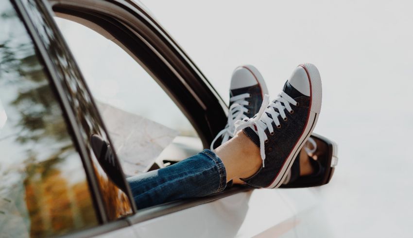 A woman's feet are hanging out of the window of a car.
