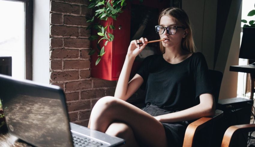 A woman is sitting in front of a laptop and smoking a cigarette.