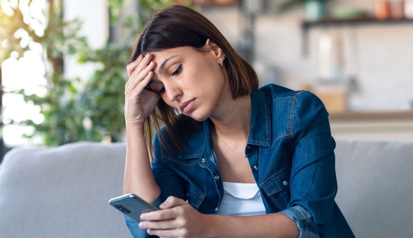 A woman is sitting on a couch and looking at her phone.
