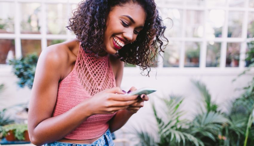 A young black woman using her cell phone in a garden.