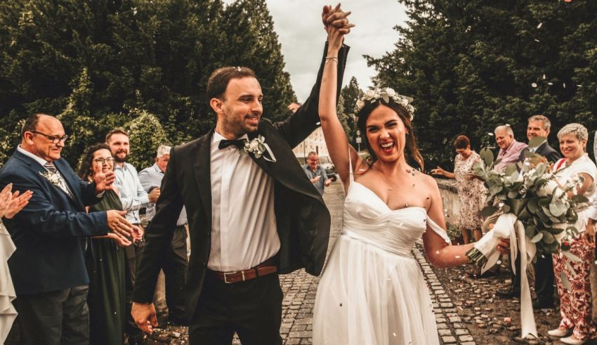 A bride and groom walking down a path with their hands in the air.