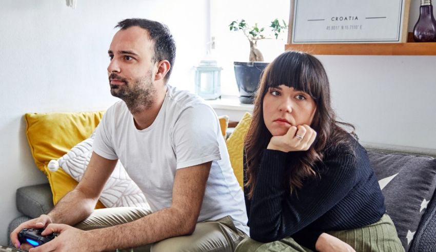 A man and woman sitting on a couch with a video game controller.