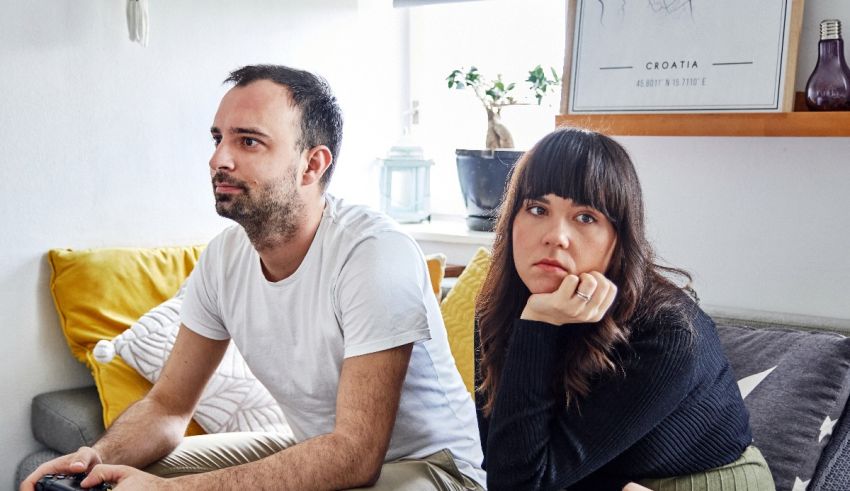 A man and woman sitting on a couch with a video game controller.