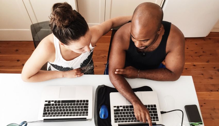 Two people working on laptops at a table.