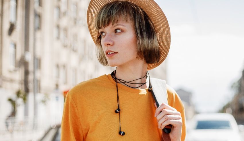 A young woman wearing a hat and carrying a bag on the street.