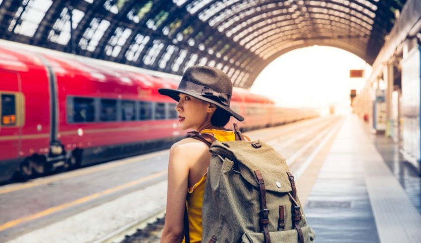 A woman with a backpack is standing at a train station.