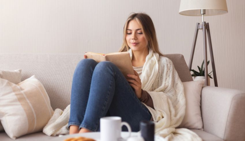 A woman is sitting on a couch reading a book.