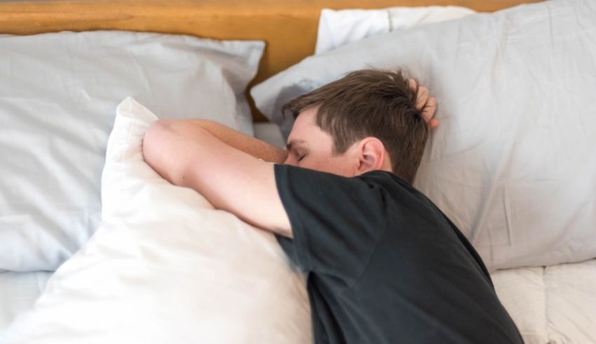 A man laying in bed with his head resting on his pillow.