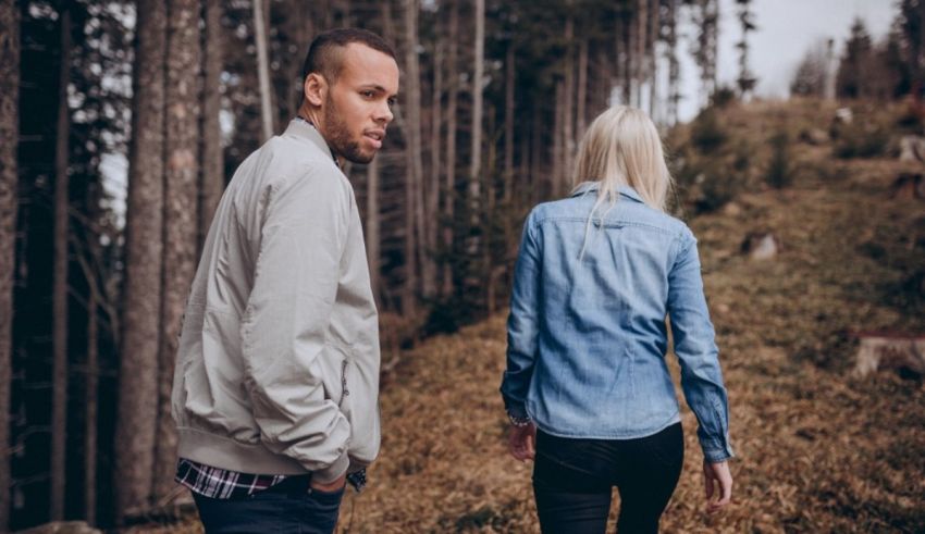 A man and woman walking through a forest.