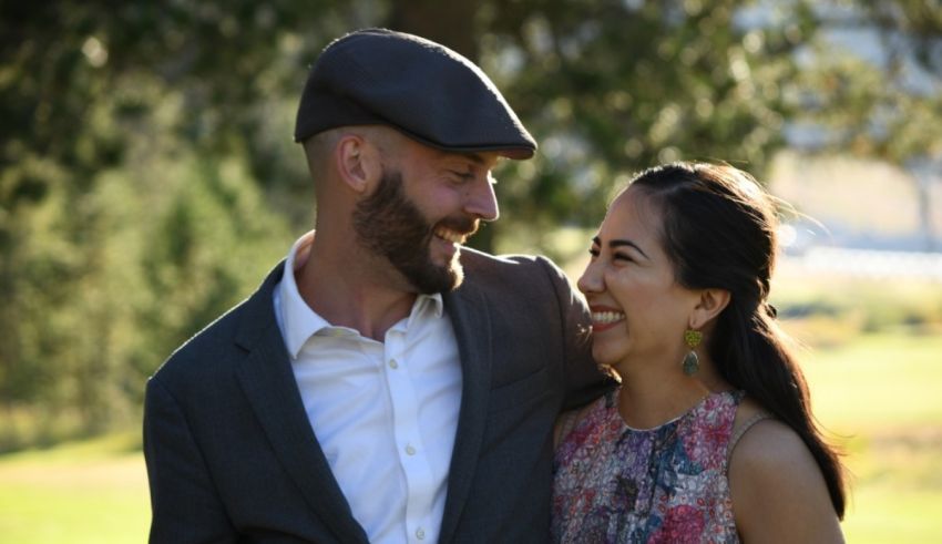 A man and woman are smiling while standing in a field.