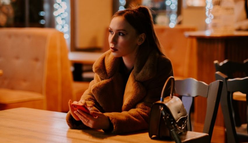 A woman sitting at a table looking at her phone.