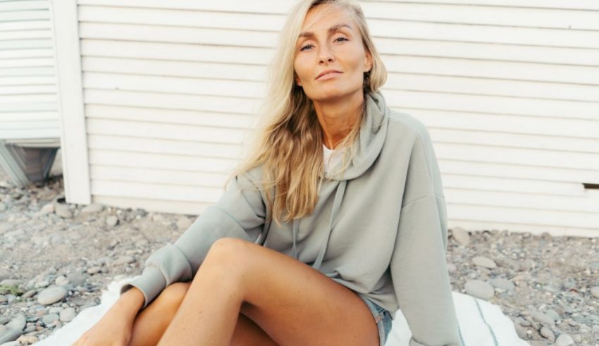 A blonde woman sitting on a blanket in front of a house.