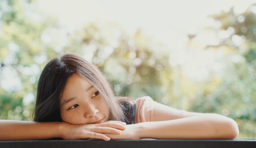A young asian girl leaning over a table.