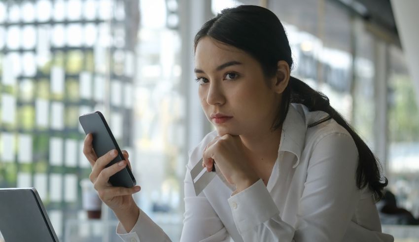 A woman is looking at her phone while sitting at a table.