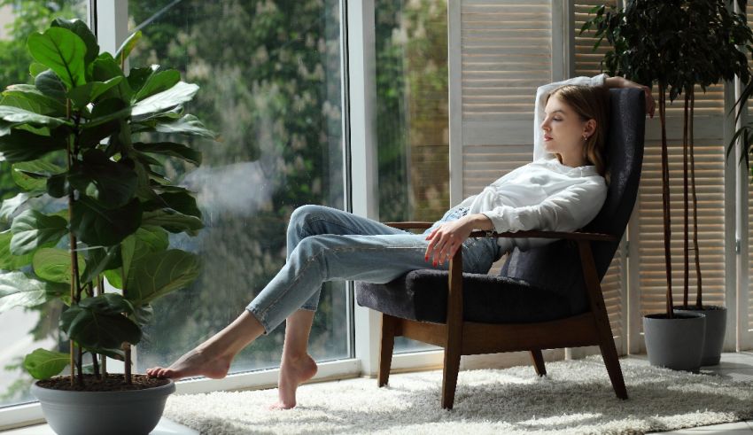A woman is sitting in a chair in front of a window.