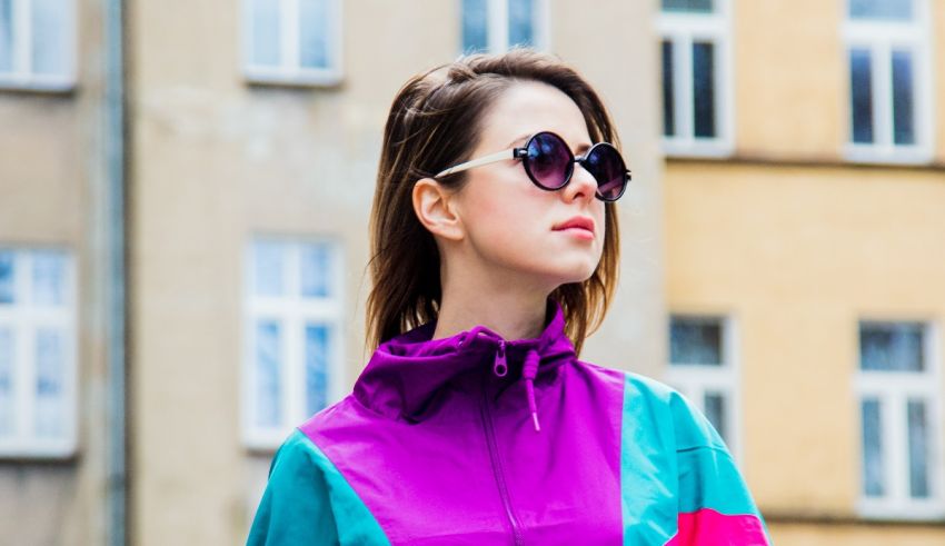 A woman wearing a purple jacket and sunglasses.