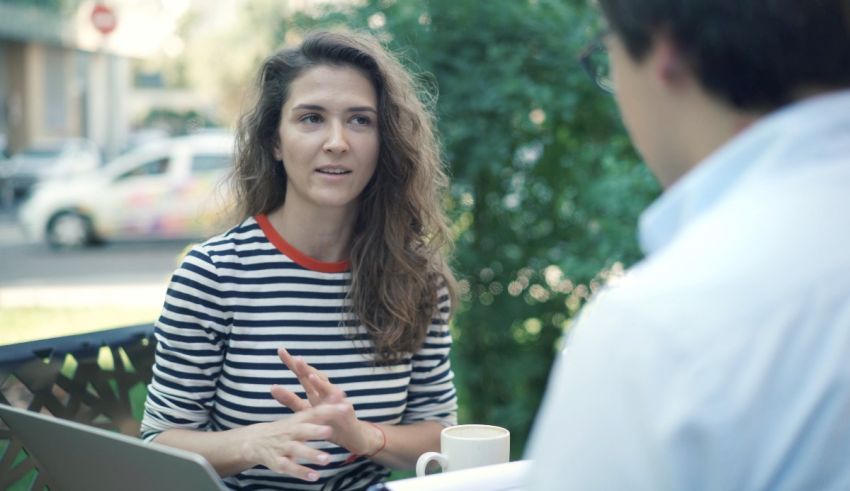 A woman is talking to a man on a laptop.