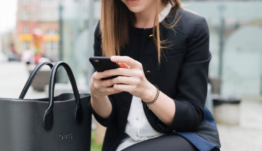 A woman sitting on a bench looking at her phone.