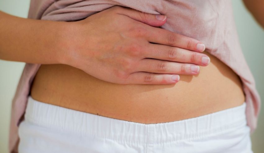 A woman is holding her stomach with her hands.