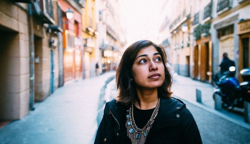A woman is standing in an alleyway looking up.