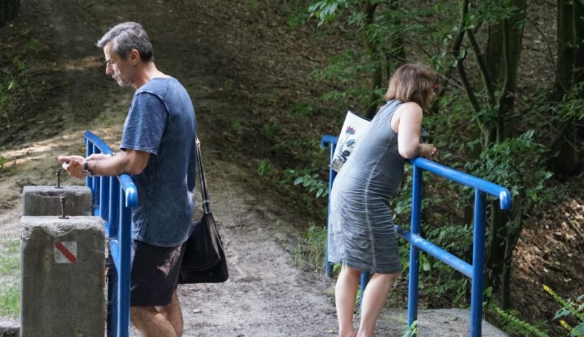 A man and woman standing on a blue railing next to a river.