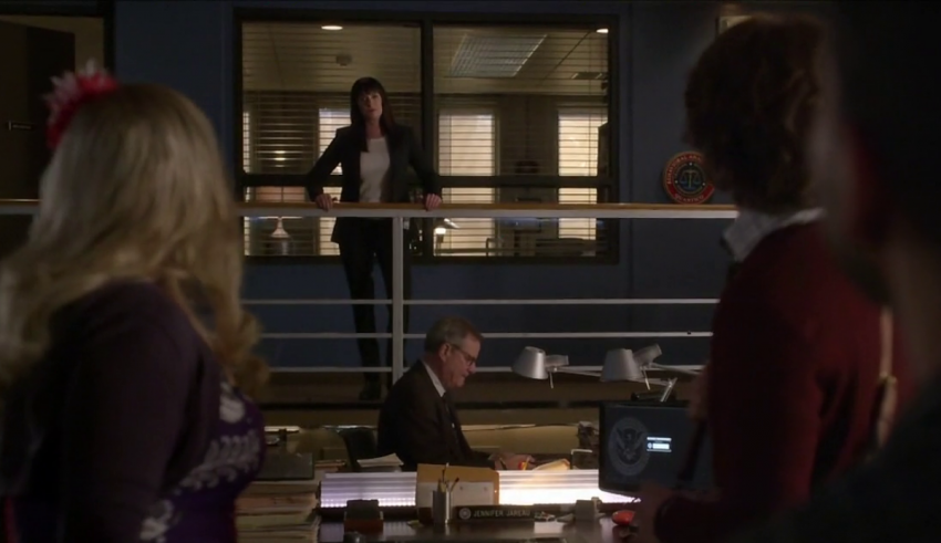 A group of people standing at a desk in an office.