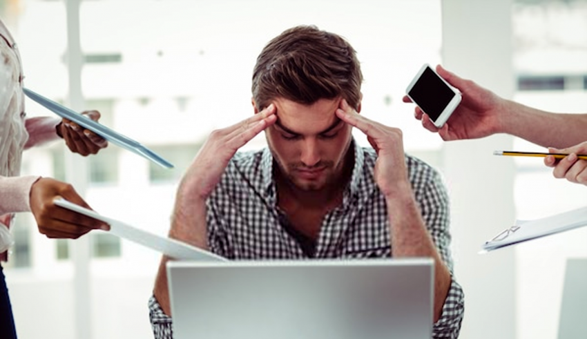 A man is holding his head in front of a group of people.
