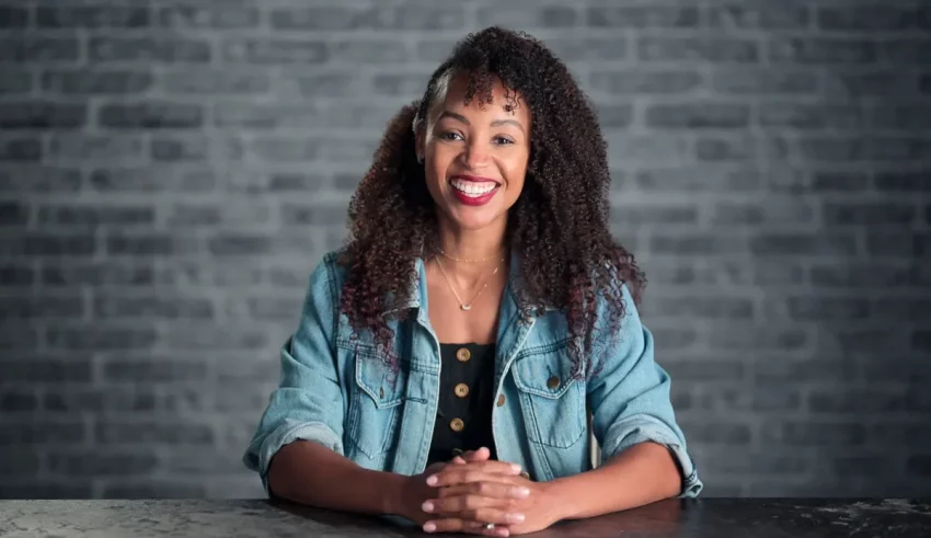 A young black woman sitting at a table and smiling.